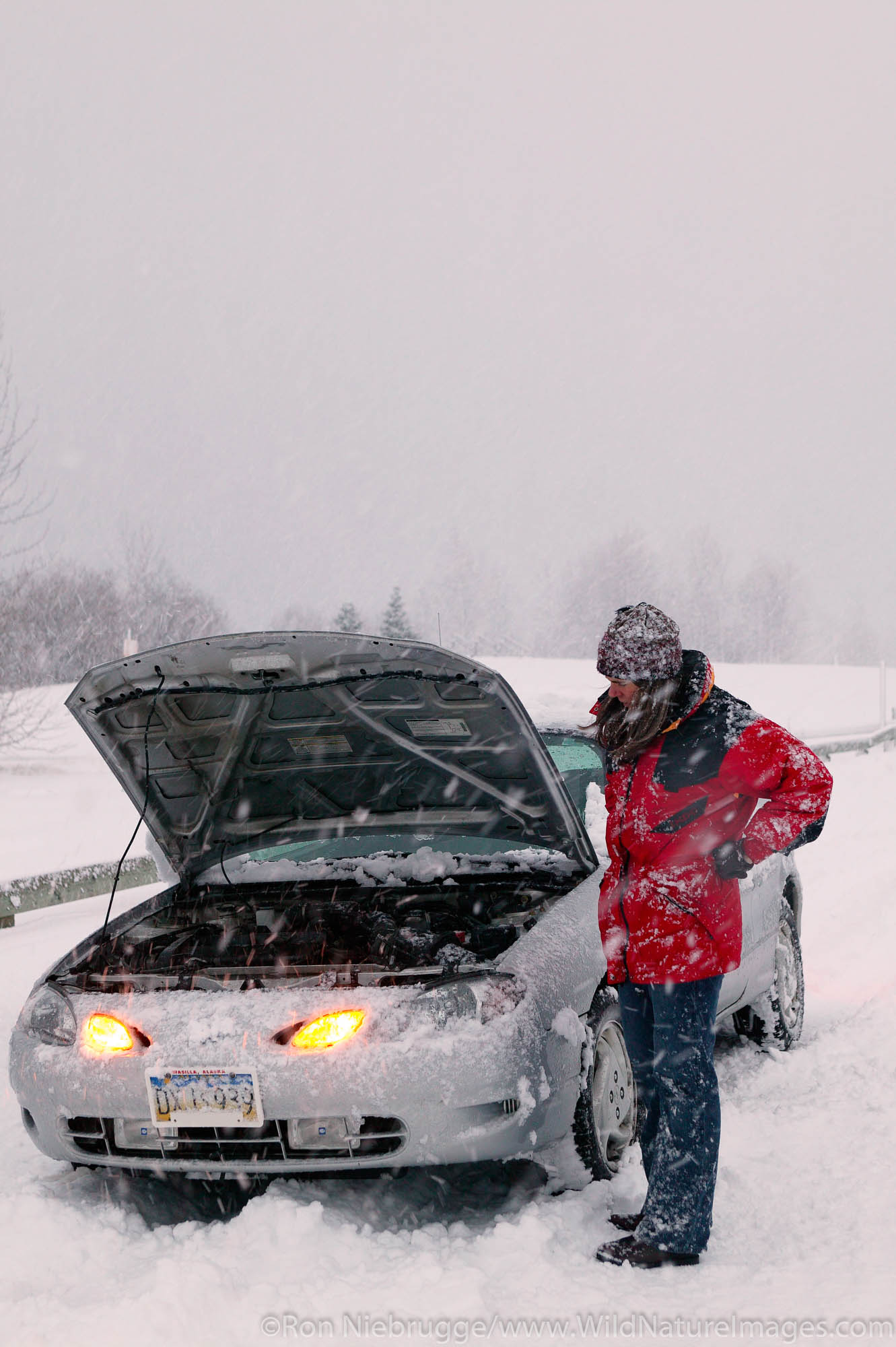 A female traveler with a disabled car during a winter snowstorm, Seward, Alaska.  (MR, PR)