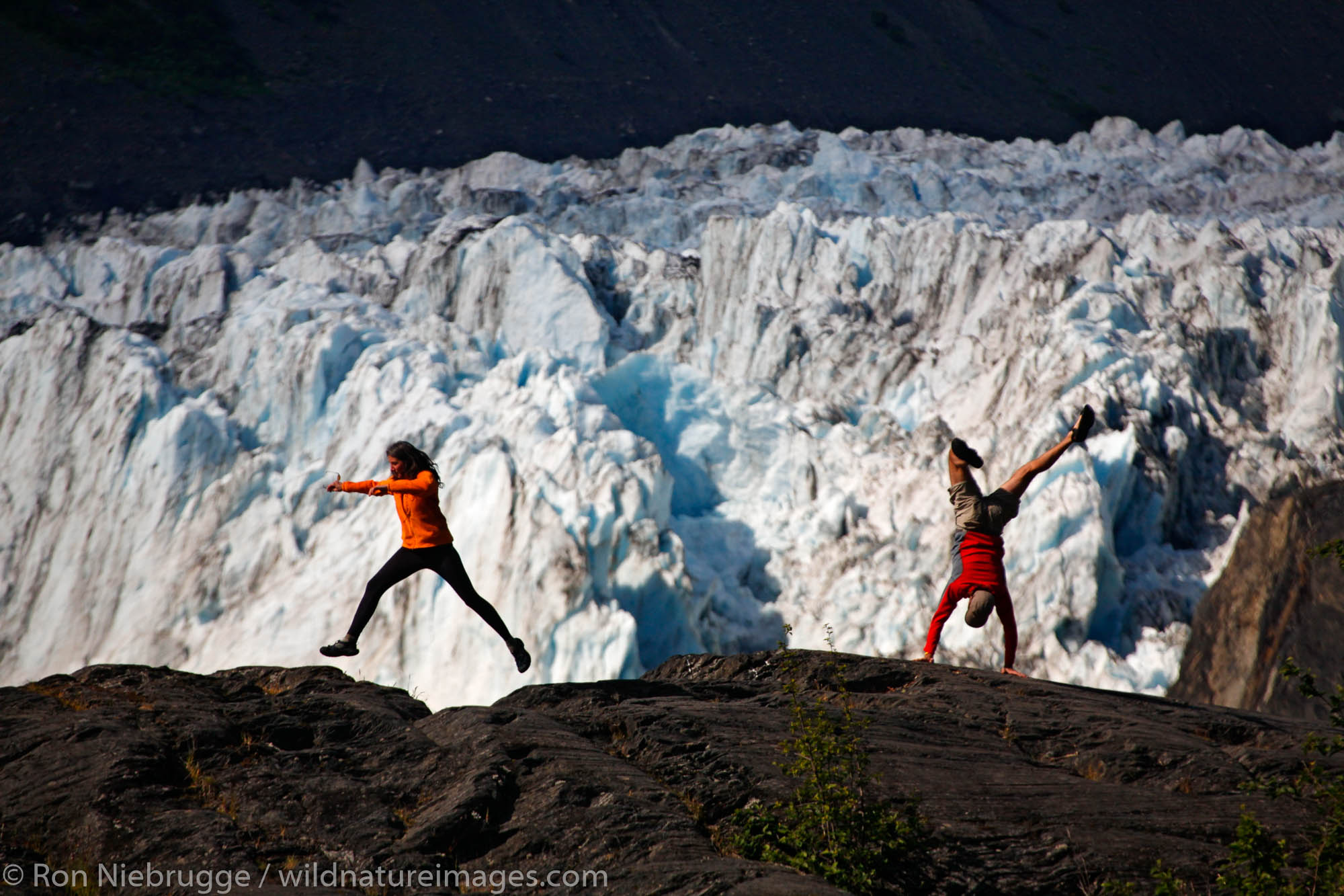 Hikers playing in front of Barry Glacier, Harrimon Fiord, Prince William Sound, Chugach National Forest, Alaska. (MR)