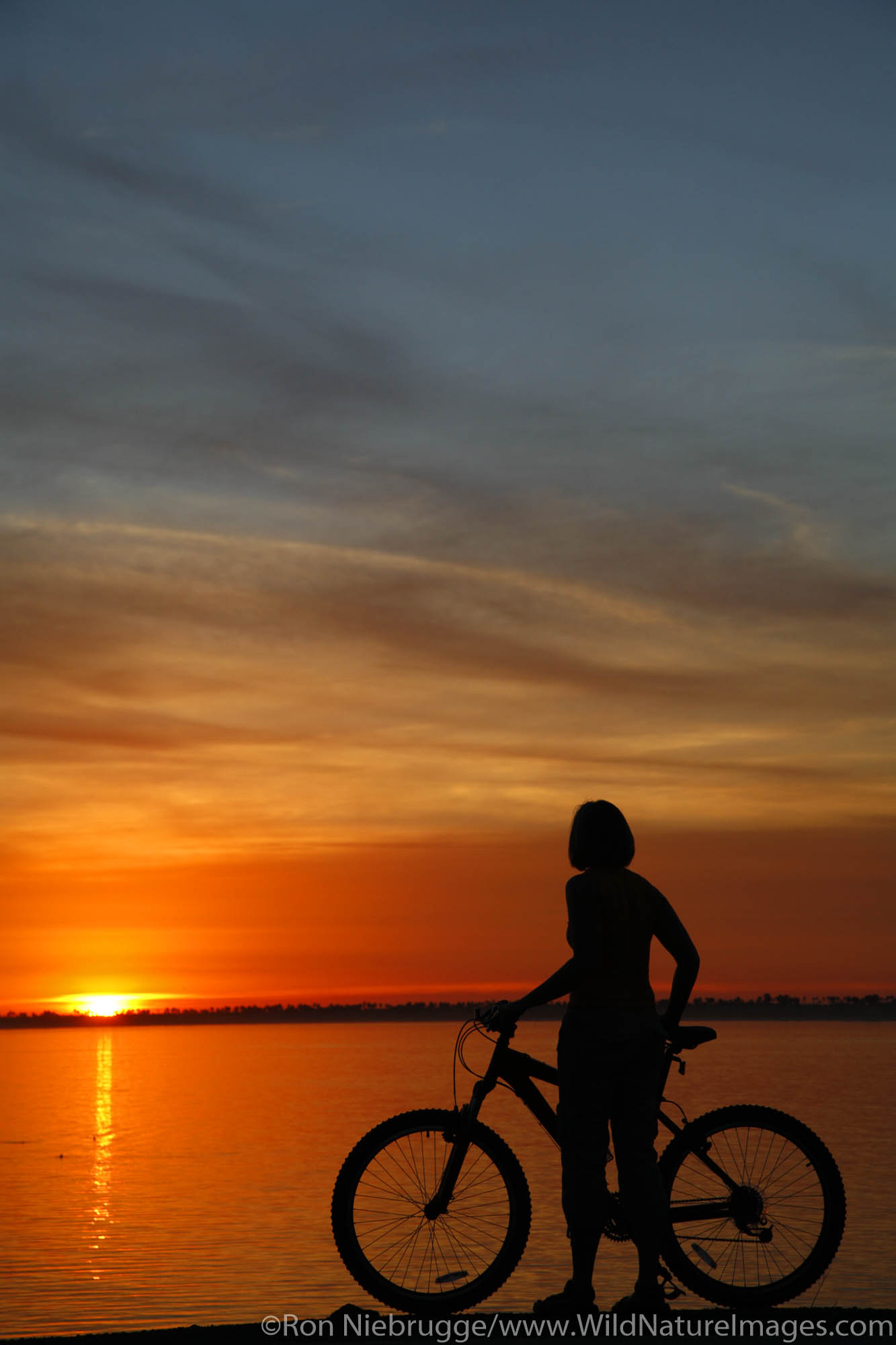 A visitor with her bike at sunset, along San Diego Bay, Chula Vista, California.  (model released)