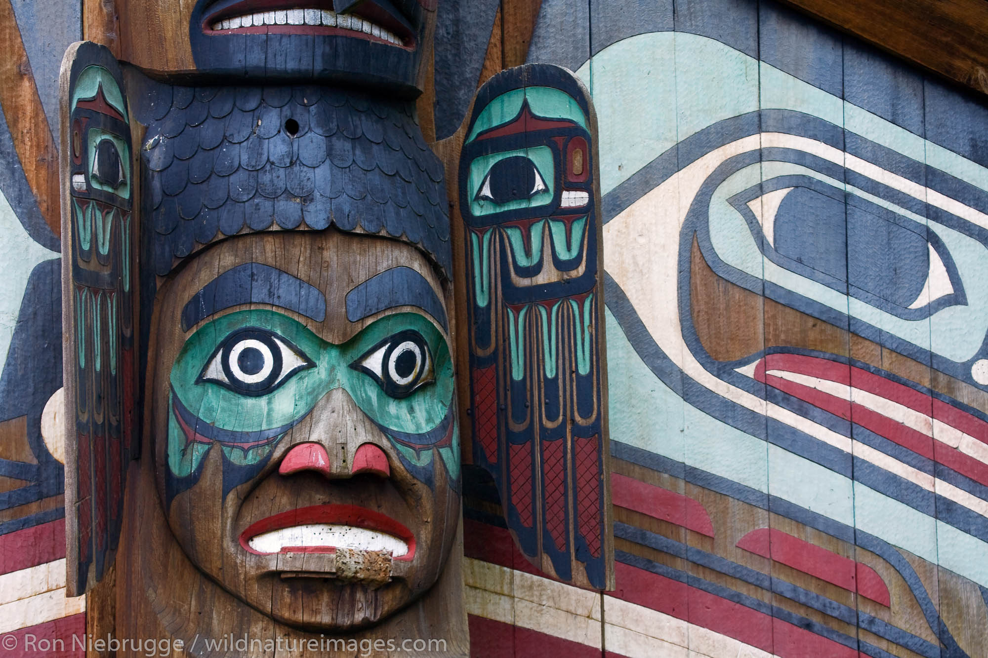 Close up of the Wandering Raven House Entrance Pole (pole 4) and the Clan house, Totem Bight State Historical Park, Ketchikan...