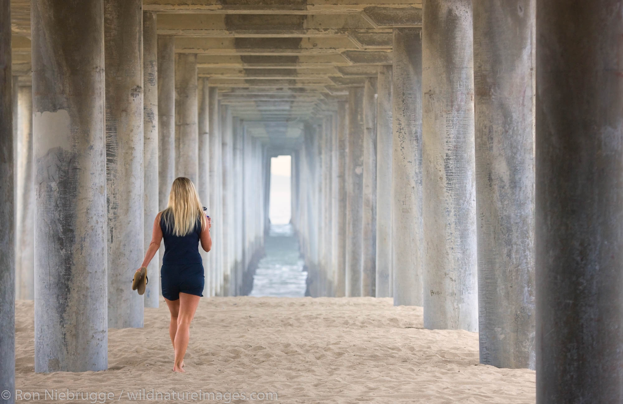 Woman walking under  the pier, Huntington Beach, Orange County, California.