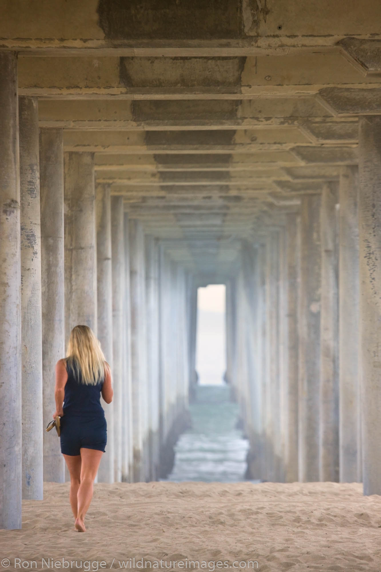 Woman walking under  the pier, Huntington Beach, Orange County, California.