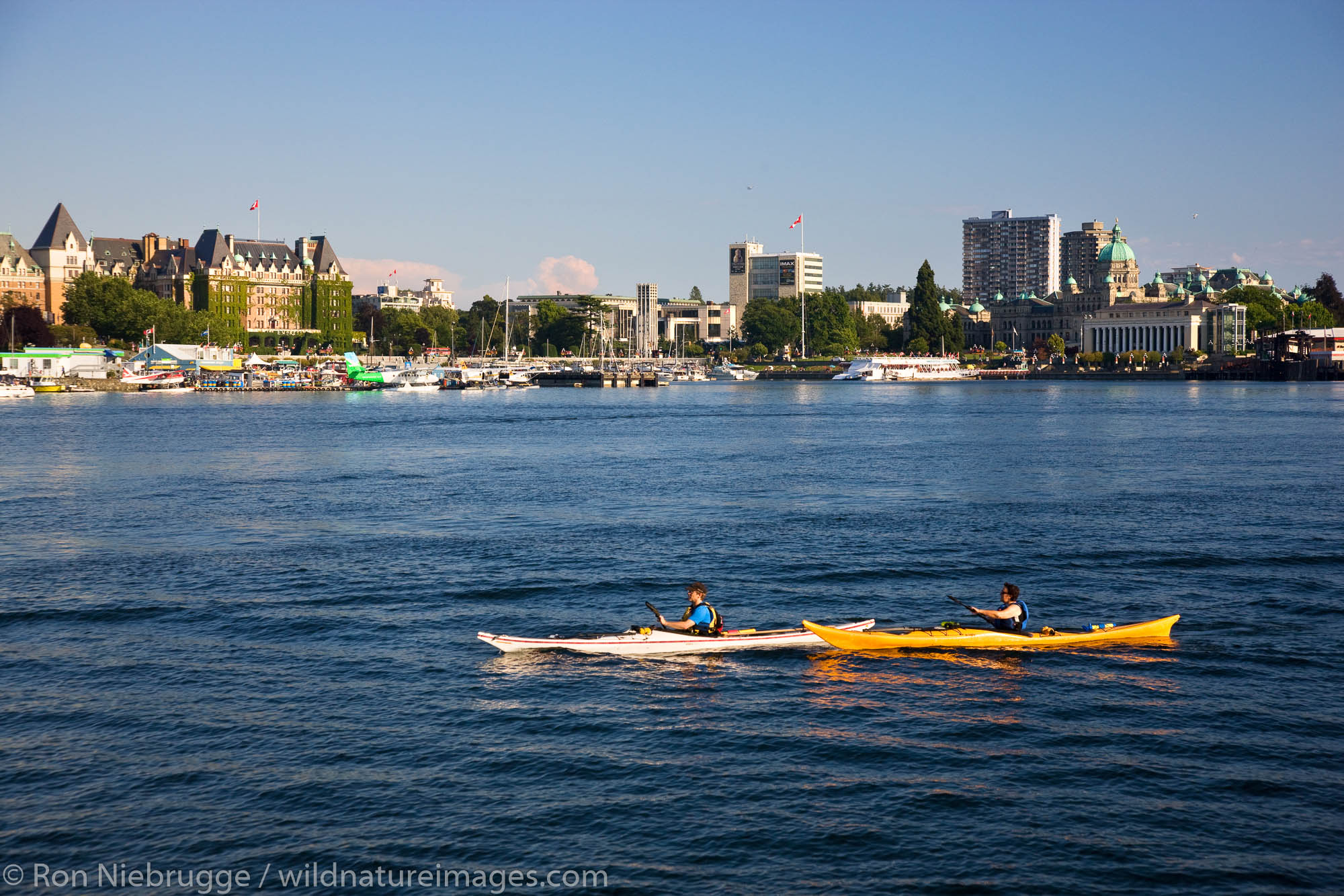 Kayakers pass Songhees Viewpoint in the Inner Harbour, Victoria, Vancouver Island, British Columbia, Canada.
