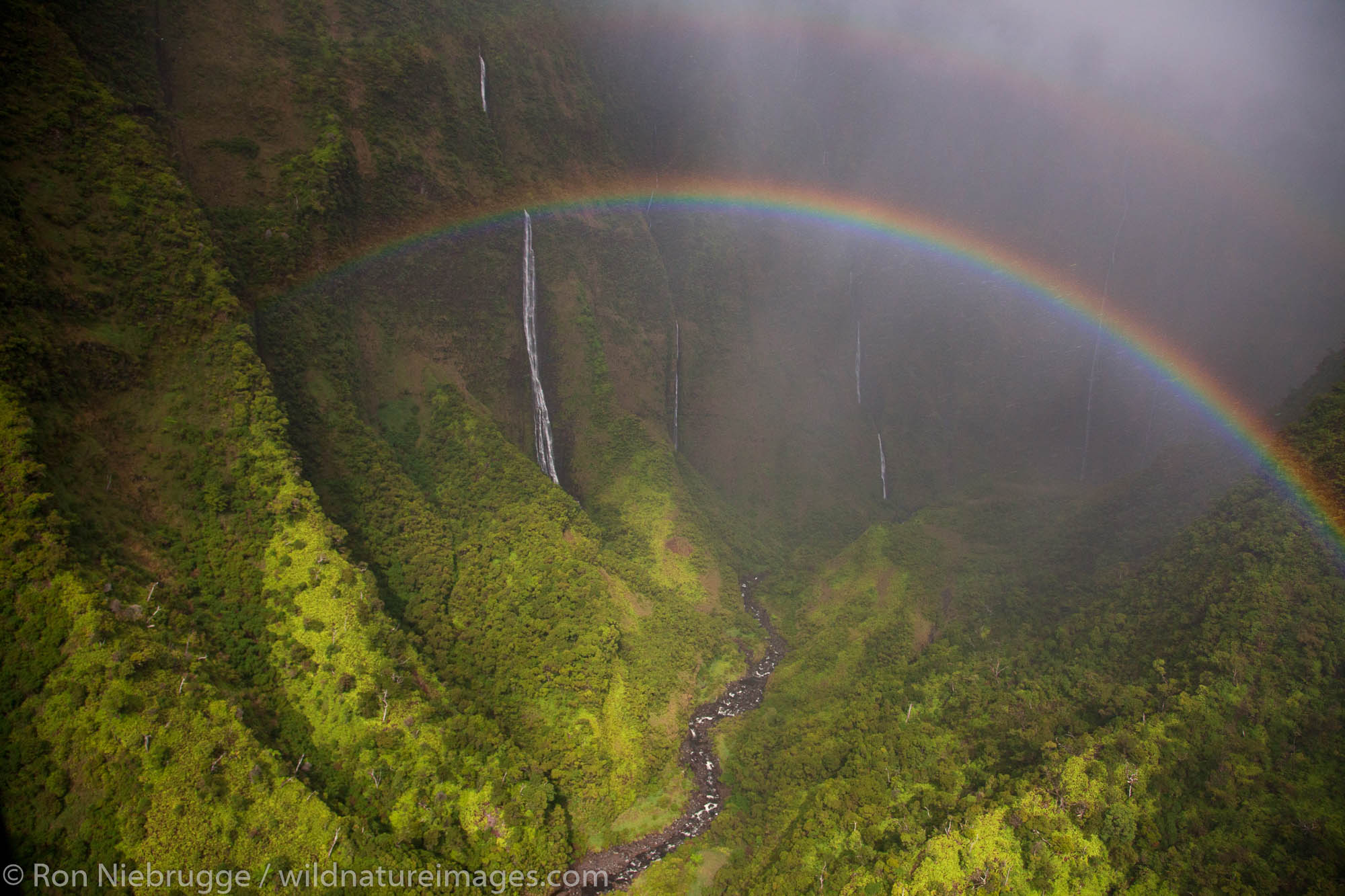 Aerial of a rainbow and waterfalls over Kauai, Hawaii.