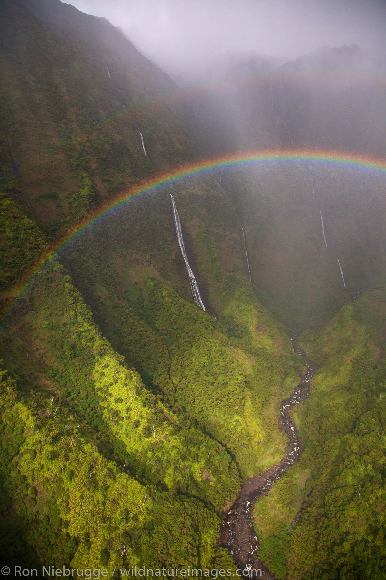 Aerial of a rainbow and waterfalls over Kauai, Hawaii.