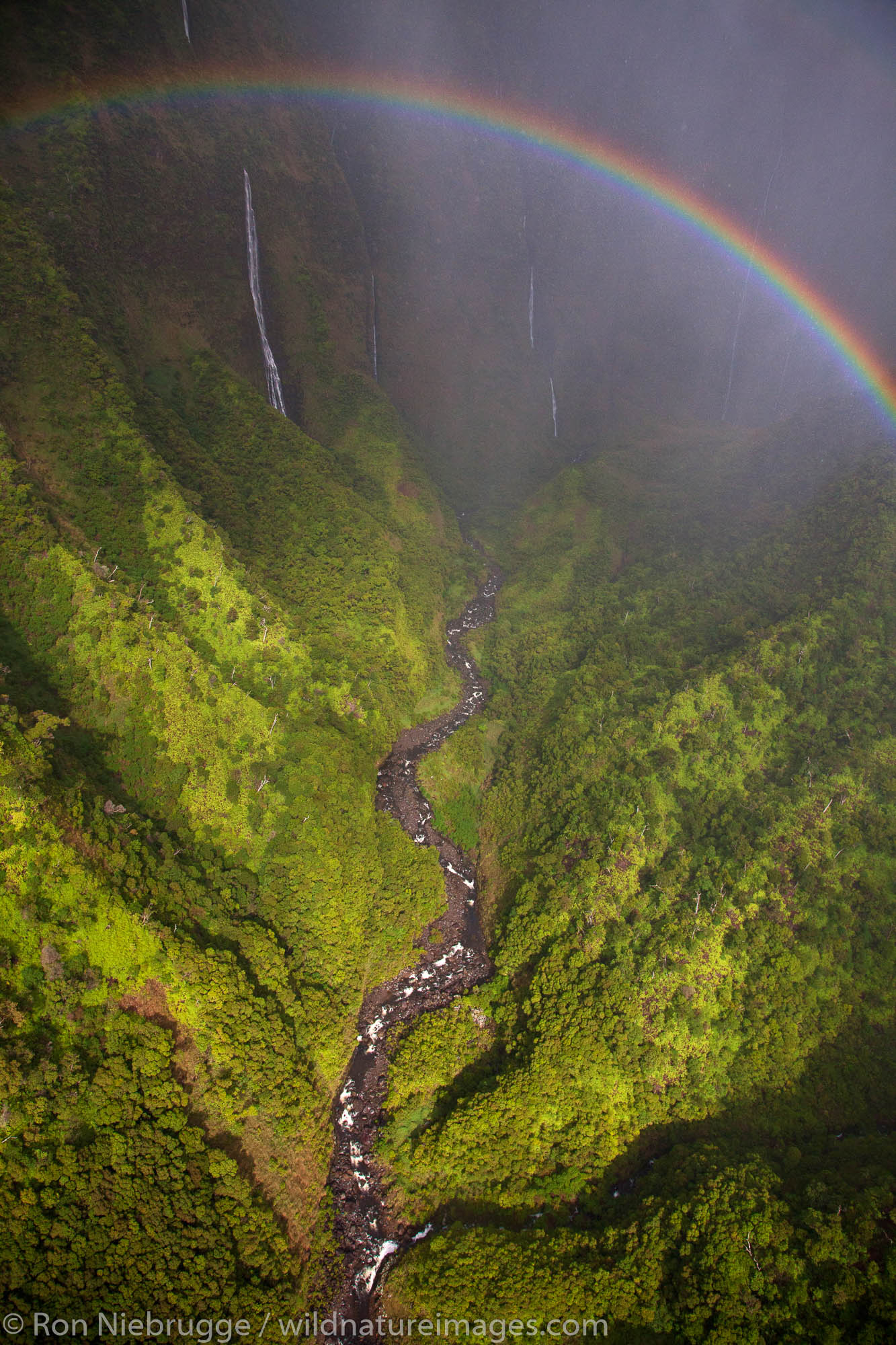 Aerial of a rainbow and waterfalls over Kauai, Hawaii.