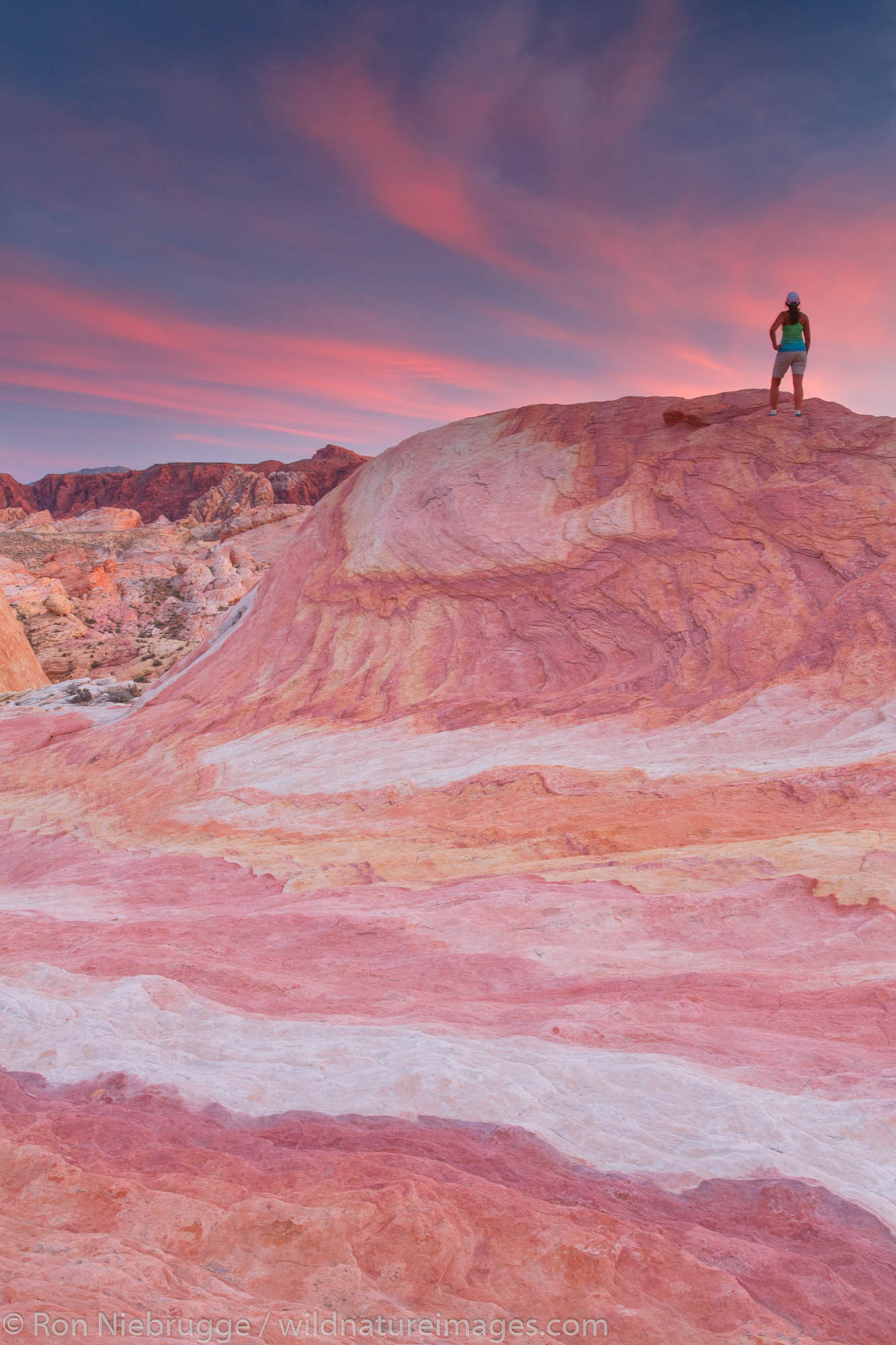 Hiker watches sunset on colorful sandstone formation, Valley of Fire State Park, near Las Vegas, Nevada. (model released)