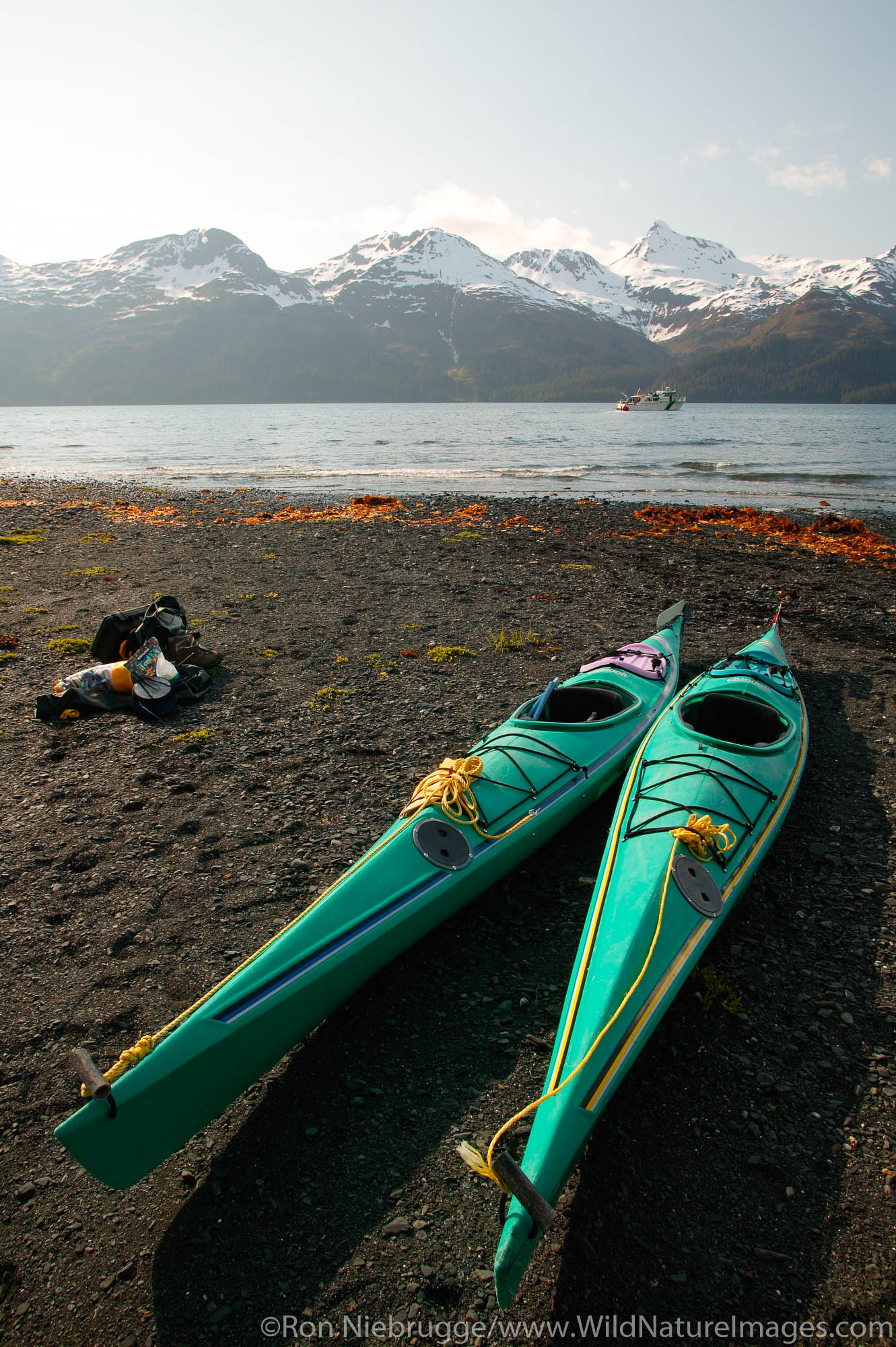 Kayaks on the beach in front of the North Arm public use cabin, Nuka Bay, with the Park Service boat Serac, Kenai Fjords National...