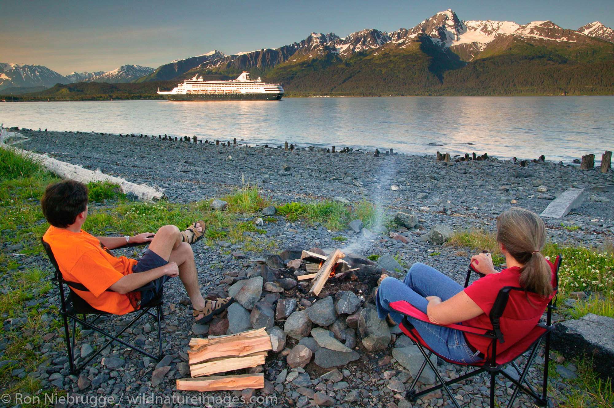 Campers enjoying campfire on the shores of Resurrection Bay as the Holland America ship Statendam departs. Seward, Alaska.  MR...